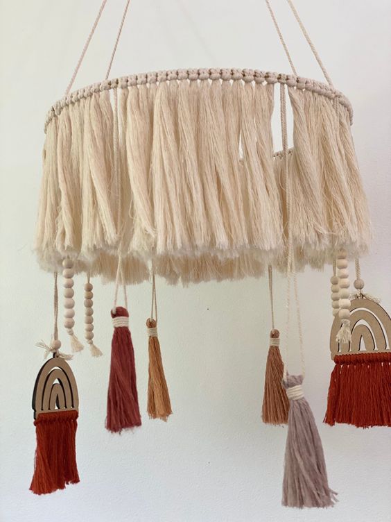 a boho nursery mobile with neutral tassels, colorful tassels and beads, rainbows is a cool idea for a boho space