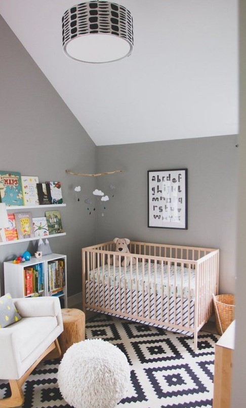 a casual nursery with grey walls and a white ceiling, a printed rug, simple furniture and a bookshelf for reading to your kid