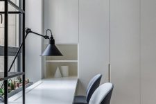 a clean minimalist home office with light grey storage units and a built-in shared desk, grey chairs and a table lamp is welcoming