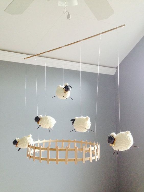 a cool kid mobile with a fence and some crochet sheep is a fun and cool idea that works for every nursery