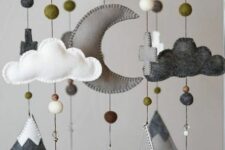 a cool woodland nursery mobile with mountains, pompoms, trees, clouds, crosses and a half moon is a stylish forest-inspired idea