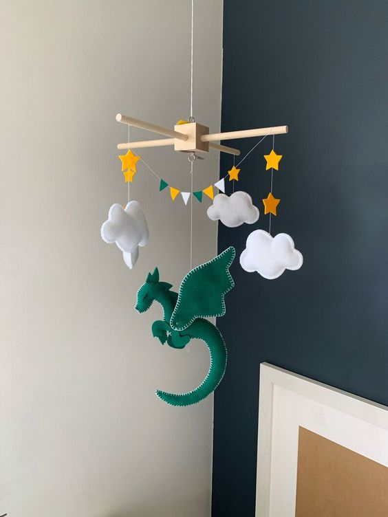a creative and bold nursery mobile with a green dragon, clouds, stars and a colorful bunting is a cool and bright solution