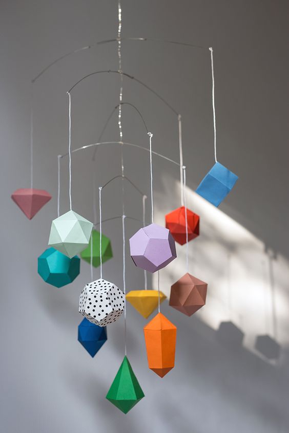 a creative and colorful 3D geometric paper mobile is a good idea for a colorful modern nursery and you can make one yourself