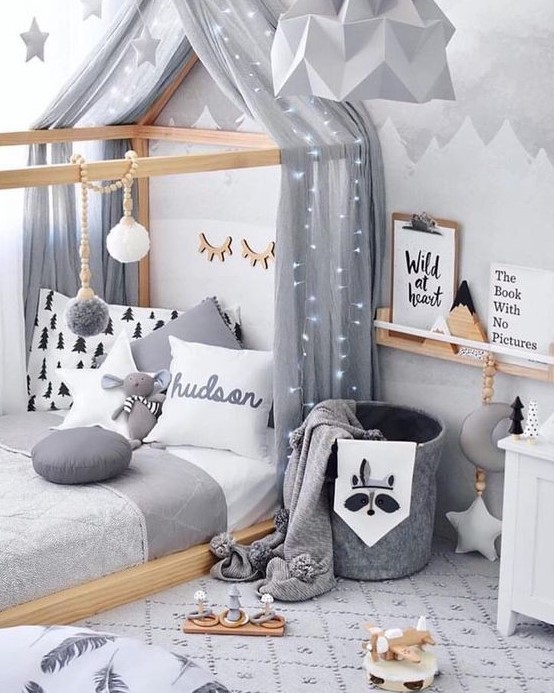 a dreamy Scandinavian bedroom with a house shaped bed, a ledge for art, a felt basket with blankets and some ligts and stars