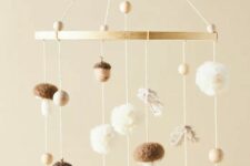 a fall-themed nursery mobile with pompoms, wooden beads, mushrooms and acorns is a cool and chic idea