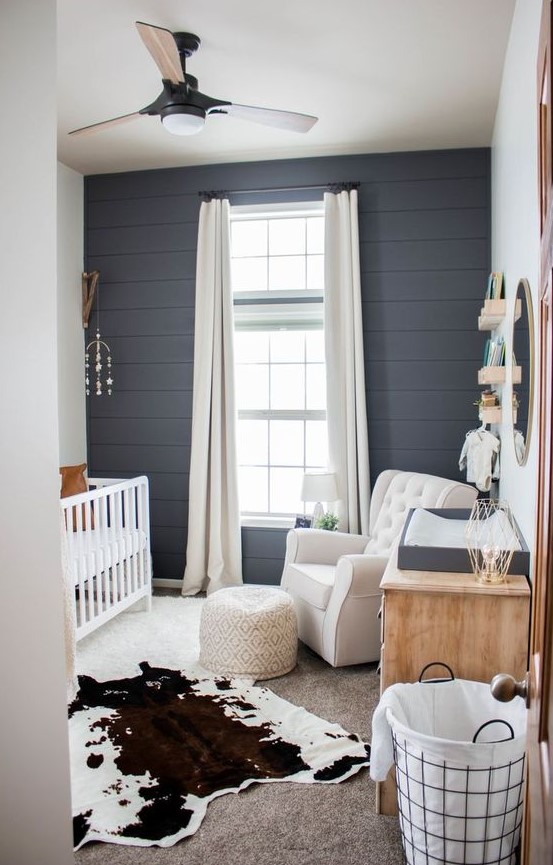 a farmhouse nursery done with a cute mobile, a printed ottoman and a faux animal skin as boho touches