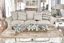 a farmhouse shabby chic living room with elegant furniture, pale greenery and vines, table lamps and antlers