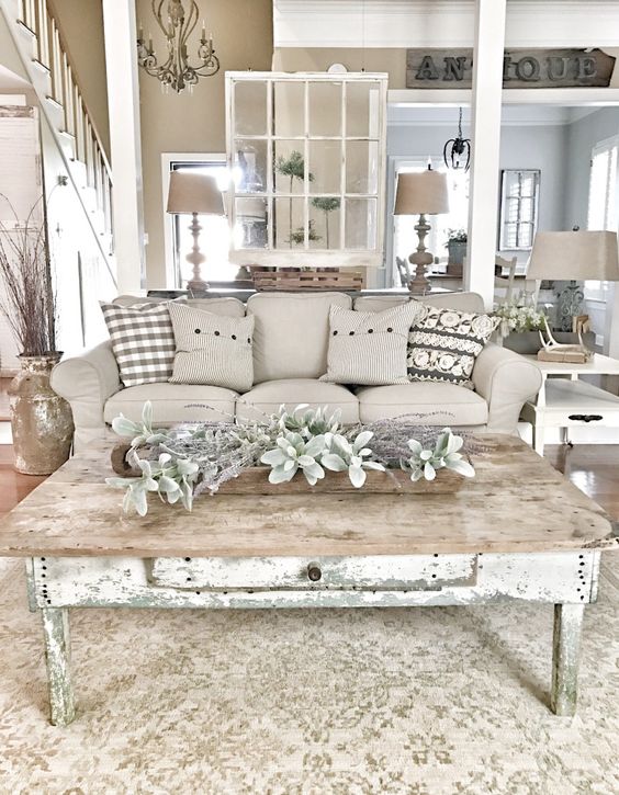 a farmhouse shabby chic living room with elegant furniture, pale greenery and vines, table lamps and antlers