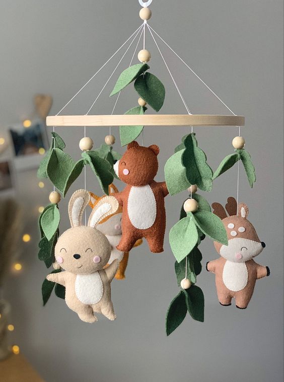 a felt woodland nursery mobile with leaves and pompoms, felt animals is a stylish and catchy idea for a woodland space