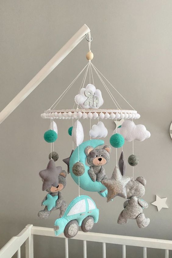a fun and colored baby mobile with clouds, stars, a car and some teddy bears done in white, grey and turquoise
