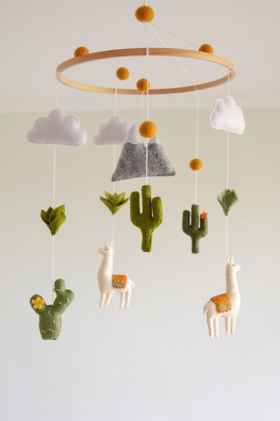 a fun desert boho mobile with felt cacti, llamas, a mountain, clouds and pompoms is a cool and bold solution for a desert space