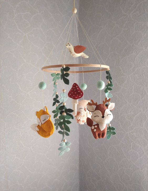 a gorgeous woodland felt mobile with deer, foxes, an owl, leaves, pompoms and mushrooms plus a bird on top for a woodland nursery