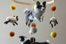 a jaw-dropping farm-themed mobile with dogs and sheep plus colorful pompoms is a very creative and fun solution