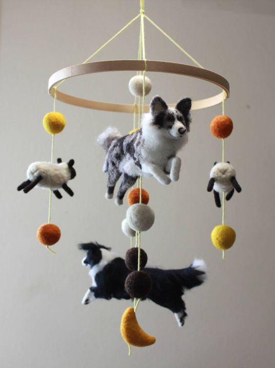 a jaw dropping farm themed mobile with dogs and sheep plus colorful pompoms is a very creative and fun solution