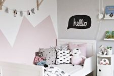 a lovely Scandinavian kid’s room with a pink and white accent wall, a white bed with printed bedding, a white shelf and a white nightstand
