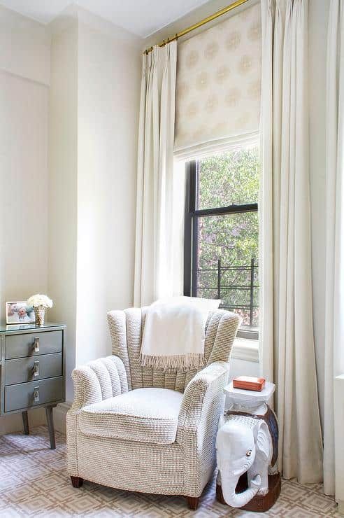 a lovely reading nook by the window styled with a printed Roman shade and creamy curtains is very lovely