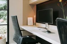 a minimalist home office with a light-stained storage cabinet, a floating desk, a black chair and a black accent wall is a welcoming space
