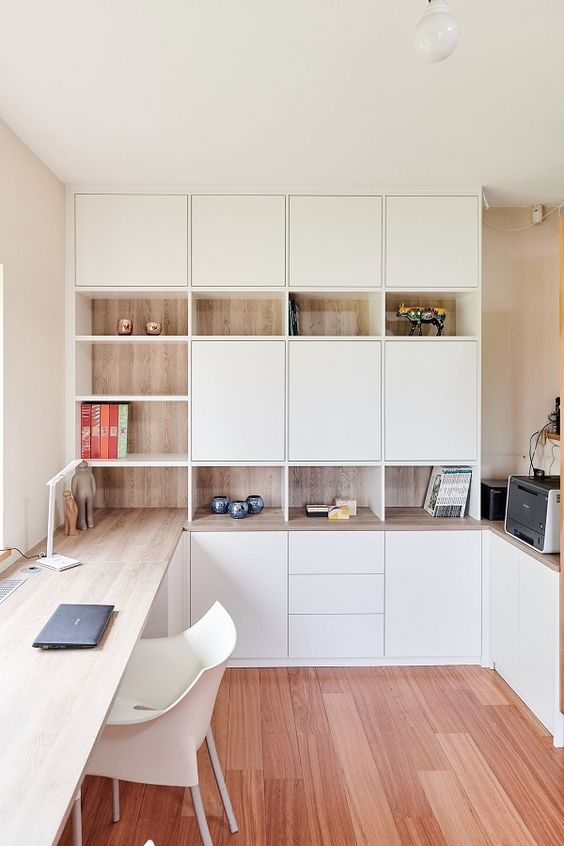 a minimalist home office with white and stained storage units, with a built-in desk and some pretty decor is very chic