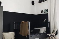 a moody kid’s space with color block walls, a black bed with monochromatic bedding, open shelves and a fabric basket, a toy car and some decor