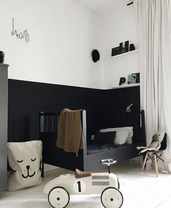 a moody kid's space with color block walls, a black bed with monochromatic bedding, open shelves and a fabric basket, a toy car and some decor