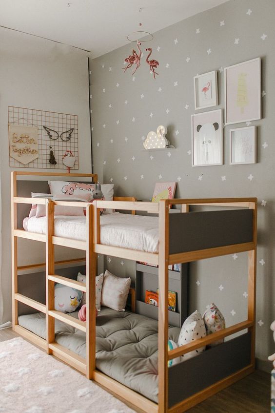 a neutral Scandi kid's room with a grey printed wall, a stained bunk bed with grey bedding and pastel pillows, a gallery wall and more decor on another wall