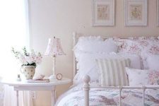 a neutral and pastel bedroom in shabby chic style, with a white forged bed, white wooden furniture, floral bedding and a gallery wall