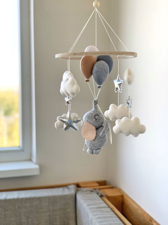 a neutral baby mobile with clouds and stars, with an elephant flying with balloons is a very cute and fun idea