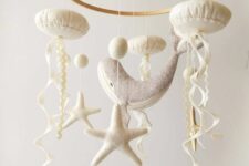 a neutral ocean-themed mobile with starfish, jellyfish, pompoms and a whale is a cool idea for a seaside or coastal nursery