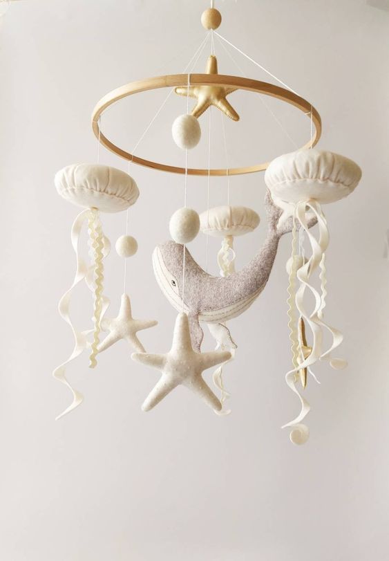 a neutral ocean themed mobile with starfish, jellyfish, pompoms and a whale is a cool idea for a seaside or coastal nursery