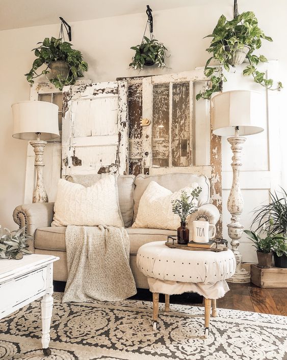 a neutral shabby chic living room with stylish furniture, potted greenery, shabby shutters and tall floor lamps