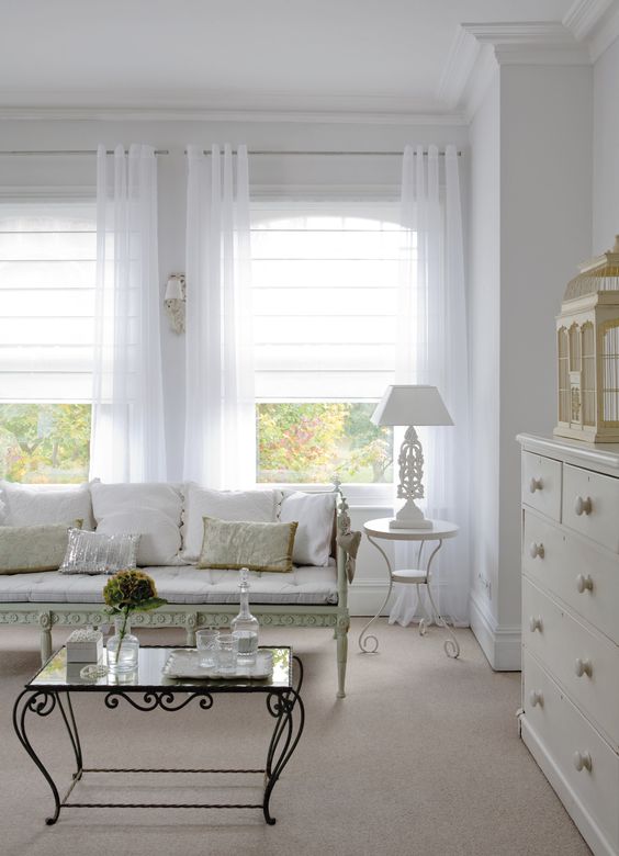 a neutral vintage room with white Roman shades and white semi sheer curtains is a very chic and stylish space that wows