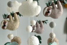 a pretty jungle nursery mobile with monstera leaves, pompoms, clouds and tardigrades is a very fun and cool idea for a tropical space