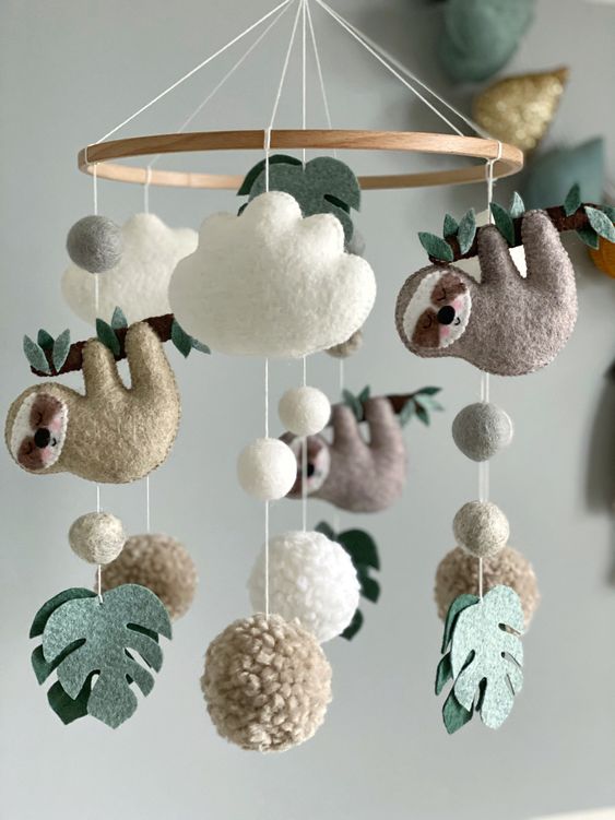 a pretty jungle nursery mobile with monstera leaves, pompoms, clouds and tardigrades is a very fun and cool idea for a tropical space
