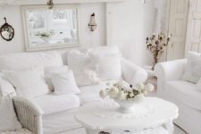 a pure white shabby chic living room with stylish furniture, a crystal chandelier, mirrors and candles is wow