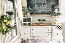 a romantic neutral shabby chic kitchen with refined furniture, a chalkboard, potted greenery and lemons for a touch of color