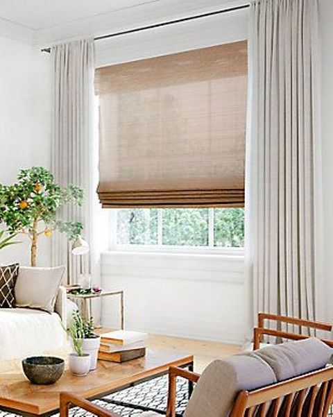 a semi sheer burlap Roman shade paired with creamy curtains makes the window look cooler and allows to keep the space private when needed