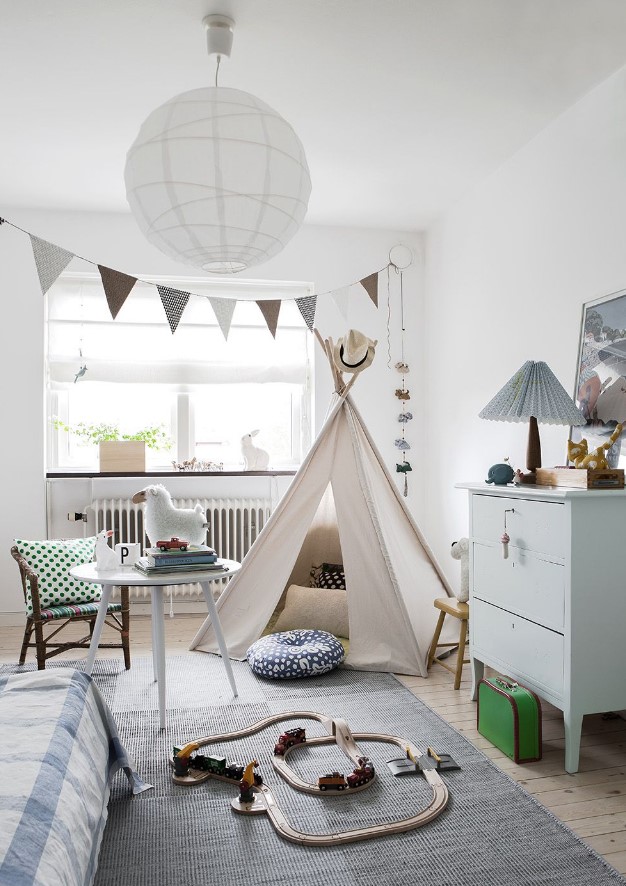 a serene Scandinavian kid's room with a bunting, a teepee, a dresser, some wooden furniture, a bed and some cute toys