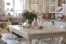 a shabby chic French country kitchen in neutrals, with a black bench, a crystal chandelier and touches of stained wood
