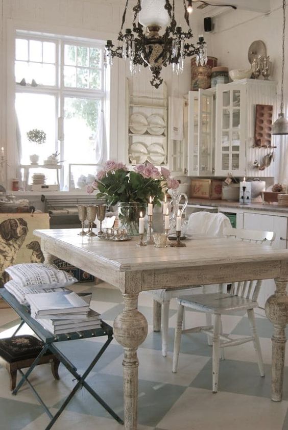 a shabby chic French country kitchen in neutrals, with a black bench, a crystal chandelier and touches of stained wood