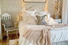 a shabby chic bedroom with a wallpaper wall, refined neutral furniture, ruffle textiles, lights and a crystal chandelier