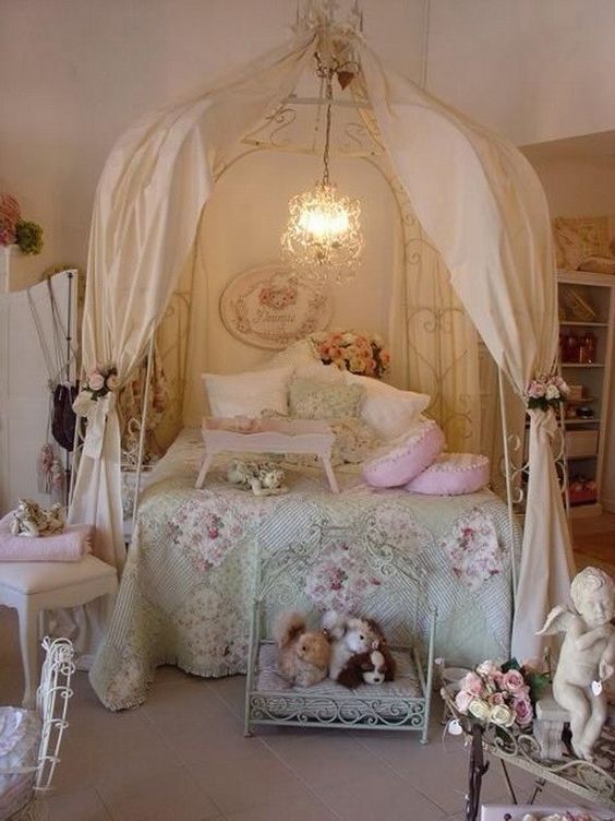 a shabby chic kids' room with a metal canopy bed, faux blooms everywhere, floral bedding and pretty vintage furniture