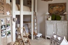 a shabby chic kid’s room with dove grey walls, shabby chic furniture, lamps, a floral chandelier, toys in baskets