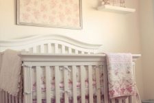 a shabby chic nursery with neutral walls and furniture, floral bedding and textiles and a paper fluff chandelier