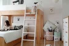 a shared Scandi kids’ room with a double bed, a ladder, some fabric baskets and buckets for storage and pastel toys