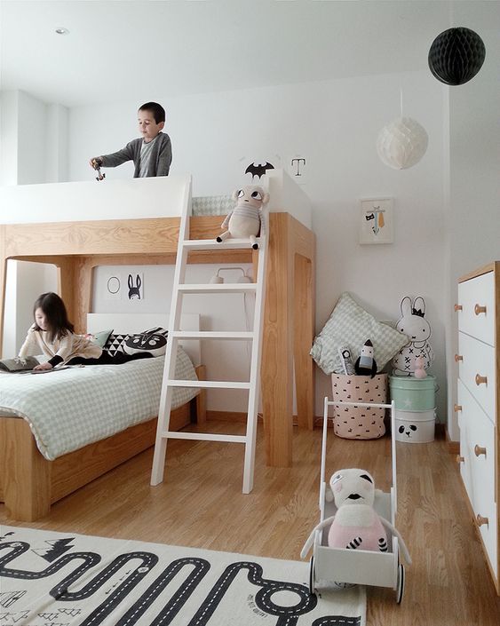 a shared Scandi kids' room with a double bed, a ladder, some fabric baskets and buckets for storage and pastel toys