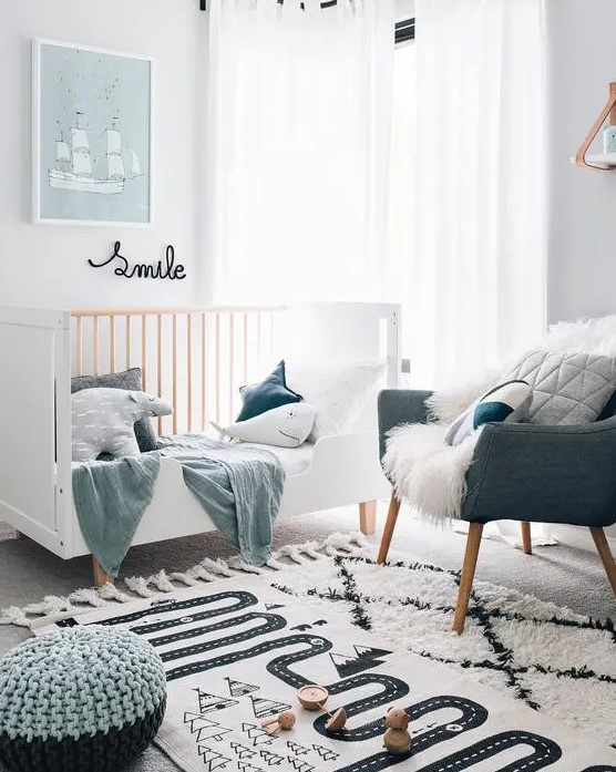 a small Scandinavian nursery with a white crib, a grey chair, pastel pillows and textiles, some artwork and layered rugs plus poufs