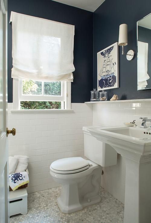 a small bathroom with black and white walls, white appliances, art and a white Roman shade that brings a traditional feel to it