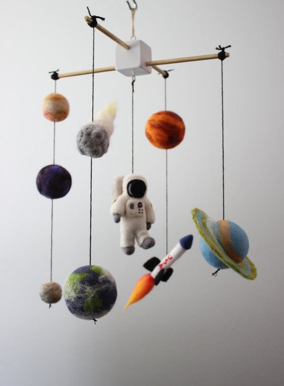 a space themed nursery mobile with planets, a rocket and a spaceman of felt is a super cool and fun idea for a space themed room