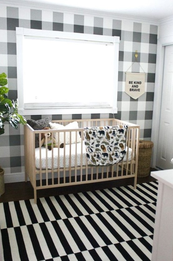 a stylish monochromatic nursery with a plaid wall and a striped rug plus potted plants to refresh the space