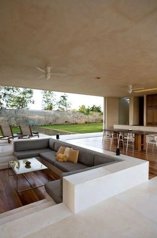 a sunken living room is divided from the dining space with a different floor level, no dividers needed